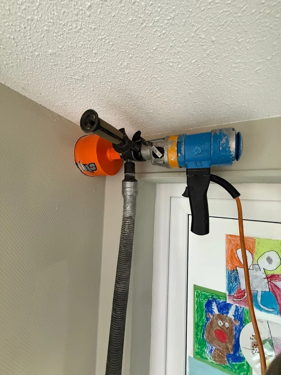 Droog diamantboren hoog in een binnenwand met stofafzuiging